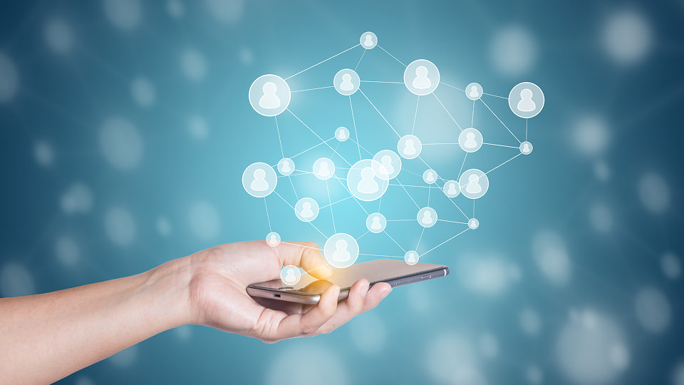 Hand holding smartphone with digital network of connected user icons, symbolizing social connections and mobile coammunication.
