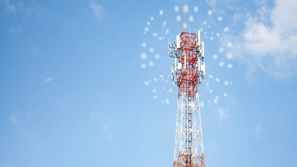 Telecommunication tower with antennas transmitting signals under a clear blue sky.